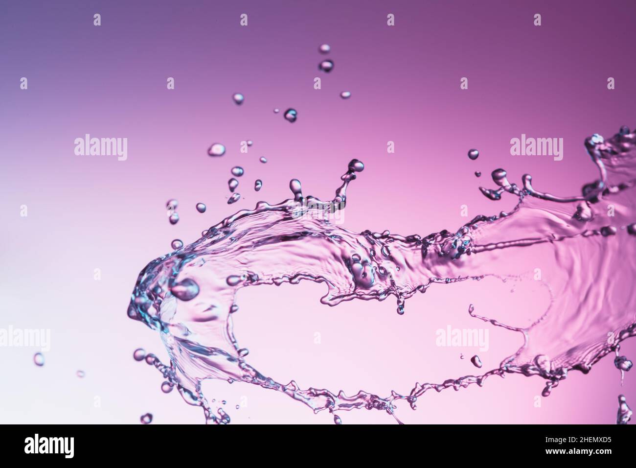 Clear water liquid splash on a purple color background Stock Photo