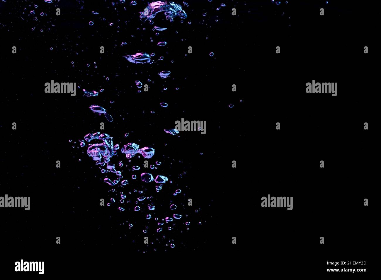 A bubble splash in transparent clear water liquid in red and blue light on a black nature background Stock Photo