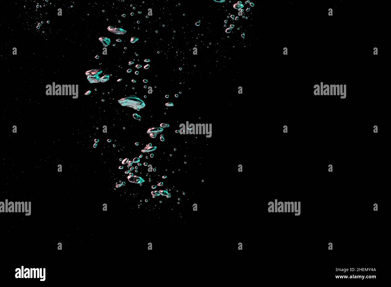 A bubble splash in transparent clear water liquid in green and blue light on a black nature background Stock Photo