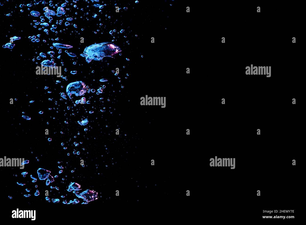 A bubble splash in transparent clear water liquid in red and blue light on a black nature background Stock Photo