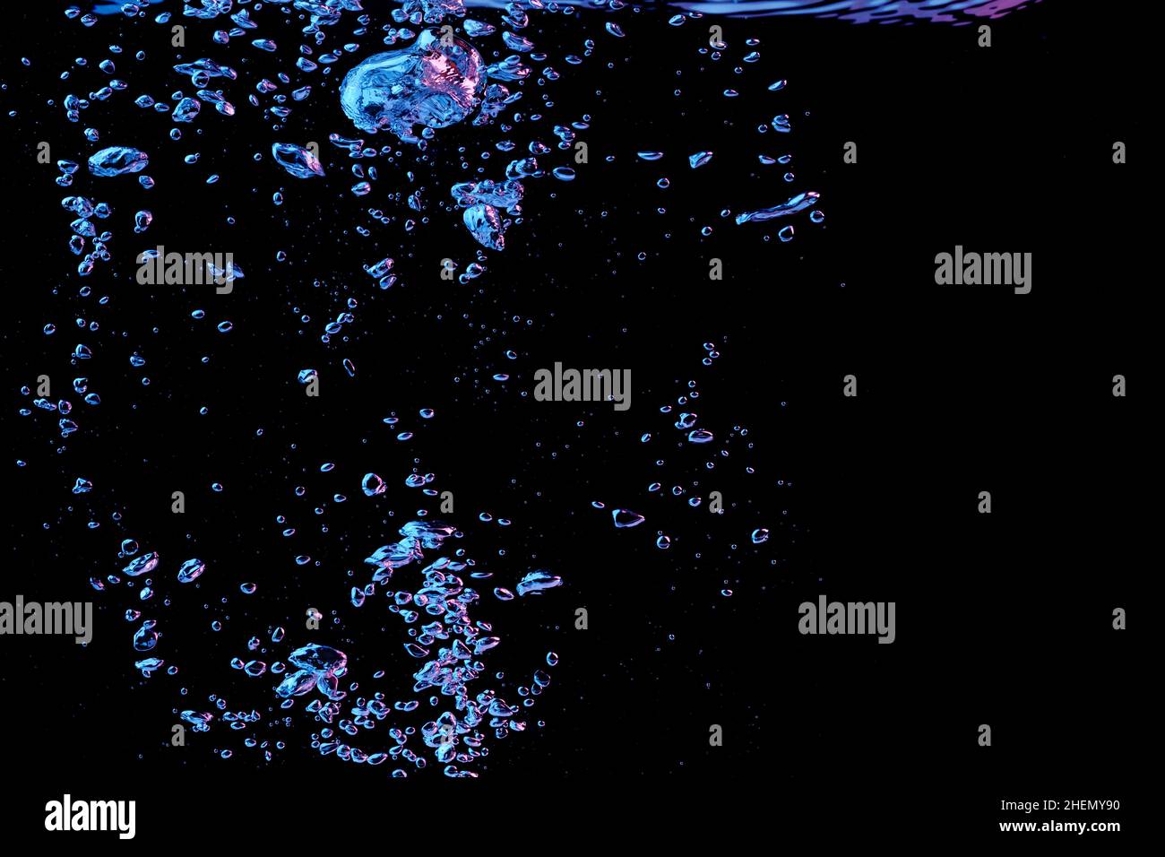 A bubble splash in transparent clear water liquid in red and blue light on a black nature background Stock Photo