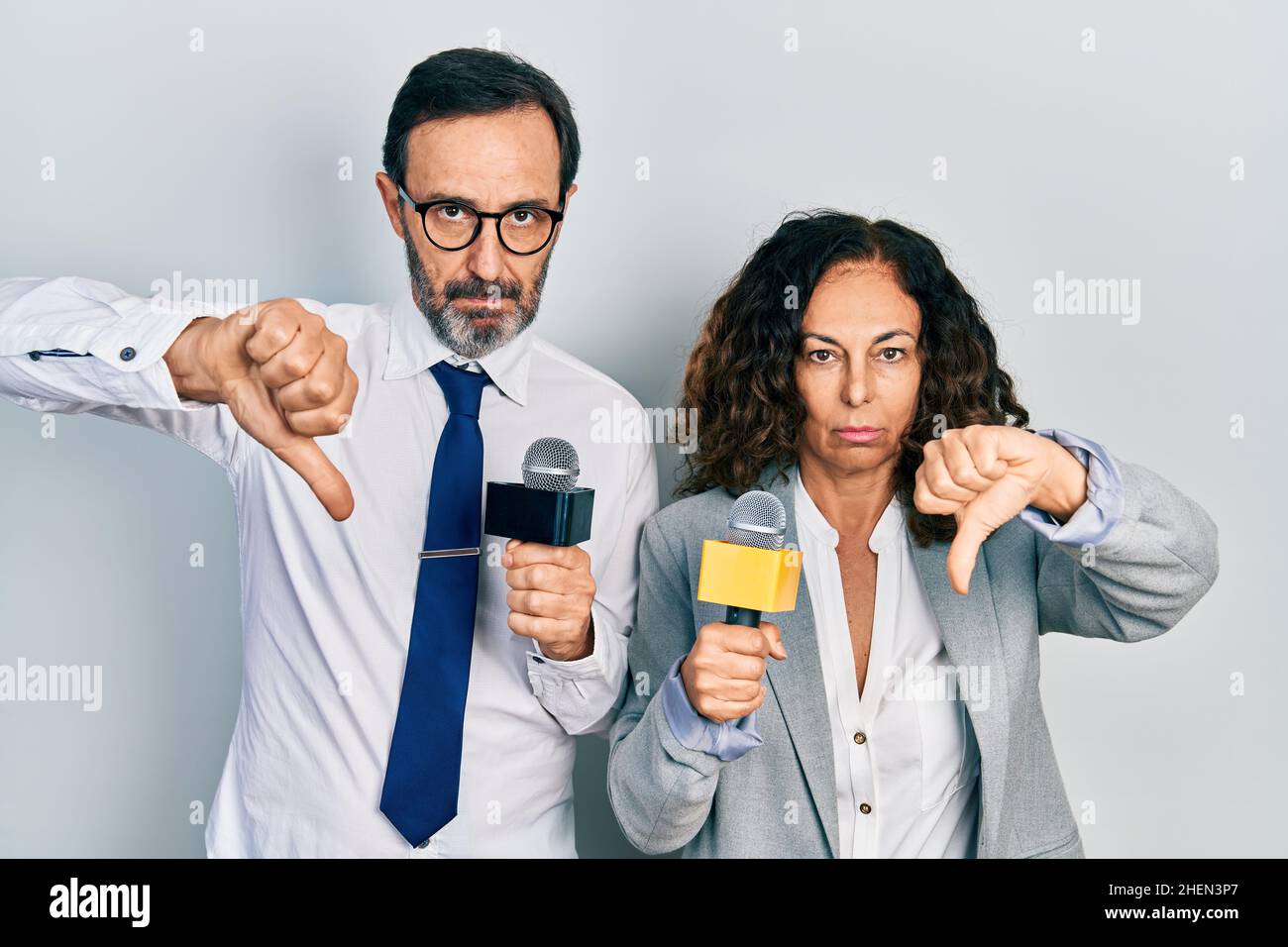 Middle age couple of hispanic woman and man holding reporter ...