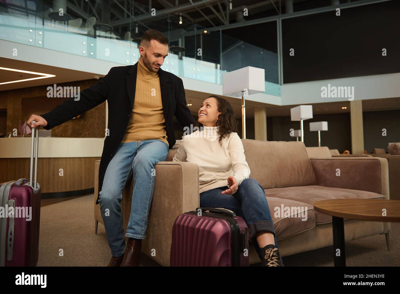Woman and man in casual clothes with suitcases sitting on armchair in the  international airport terminal lounge, looking at each other, discussing  for Stock Photo - Alamy
