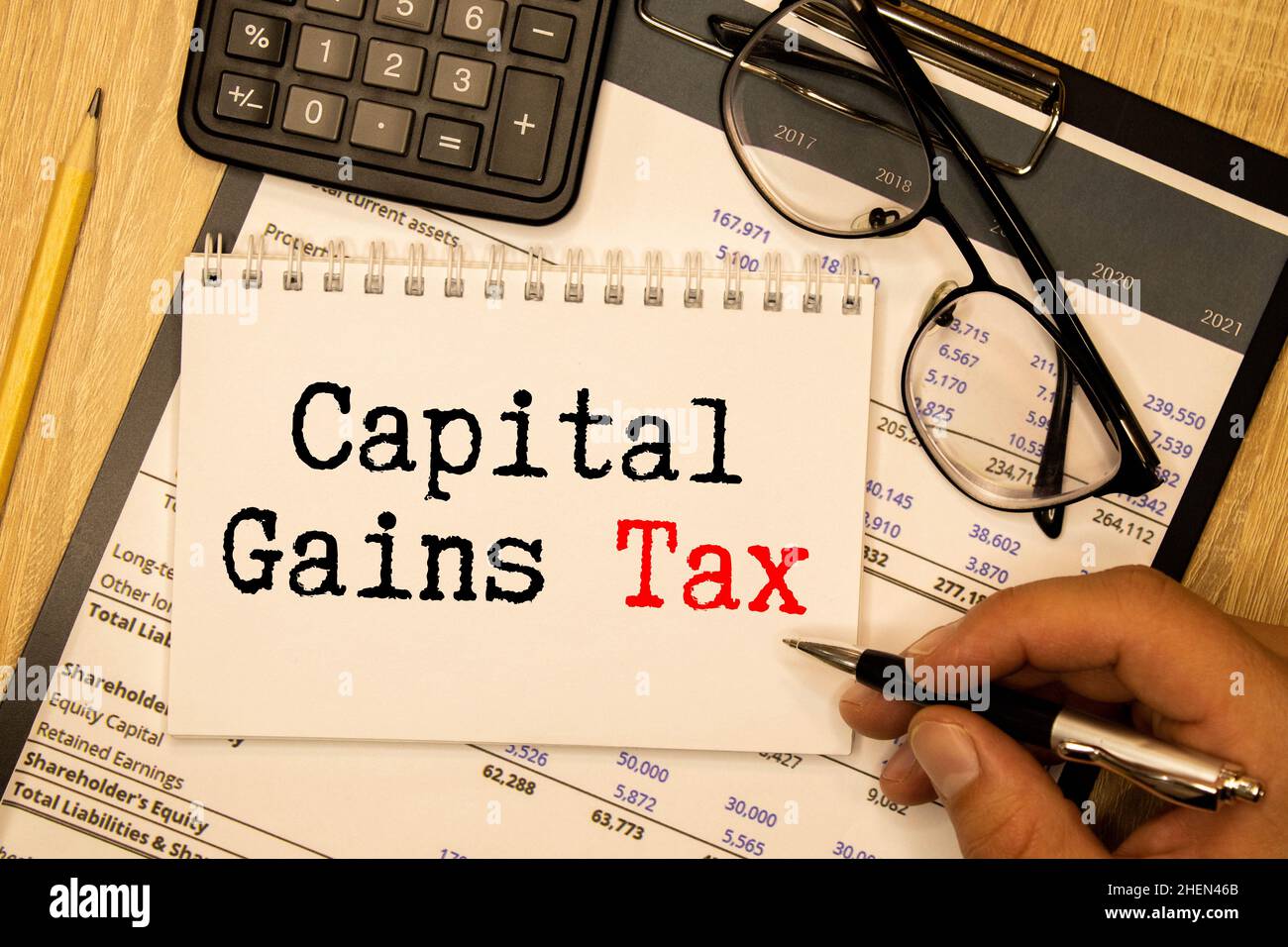 sentence capital gains tax written with chalk on a blackboard, on a table with typewriter. Stock Photo