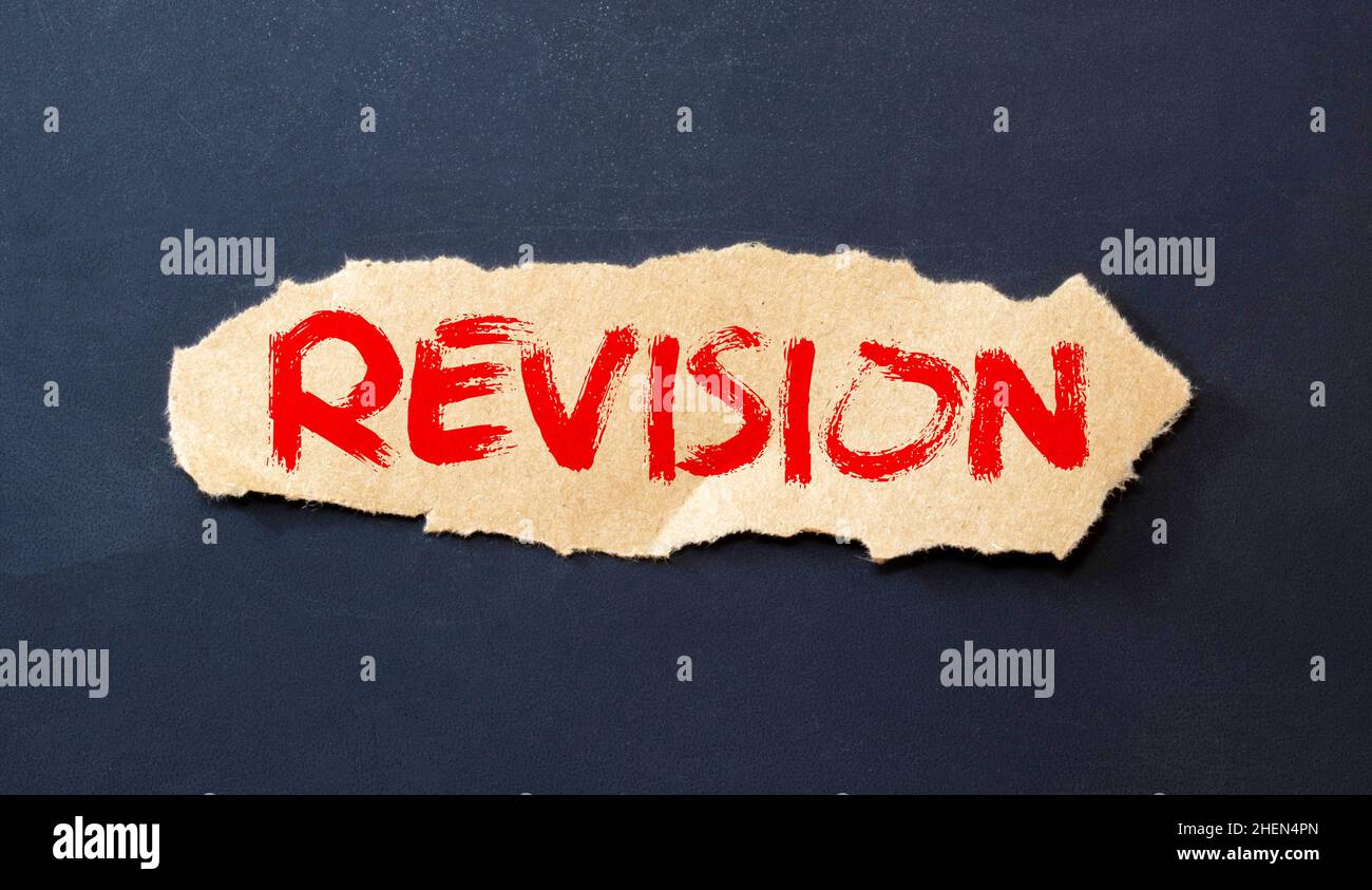 Beneath the torn strip of kraft paper attached with a red button is a white paper labeled REVISION. Stock Photo