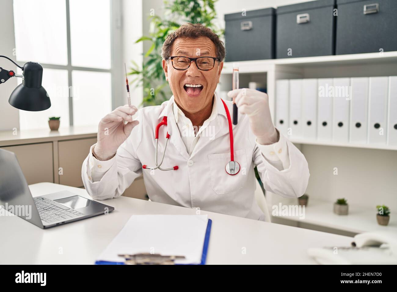 Senior doctor man holding syringe and blood sample smiling and laughing
