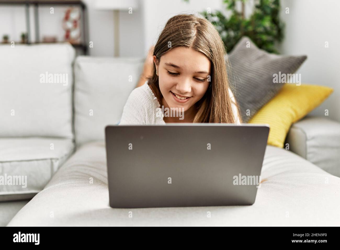 Adorable girl using laptop lying on sofa at home Stock Photo - Alamy