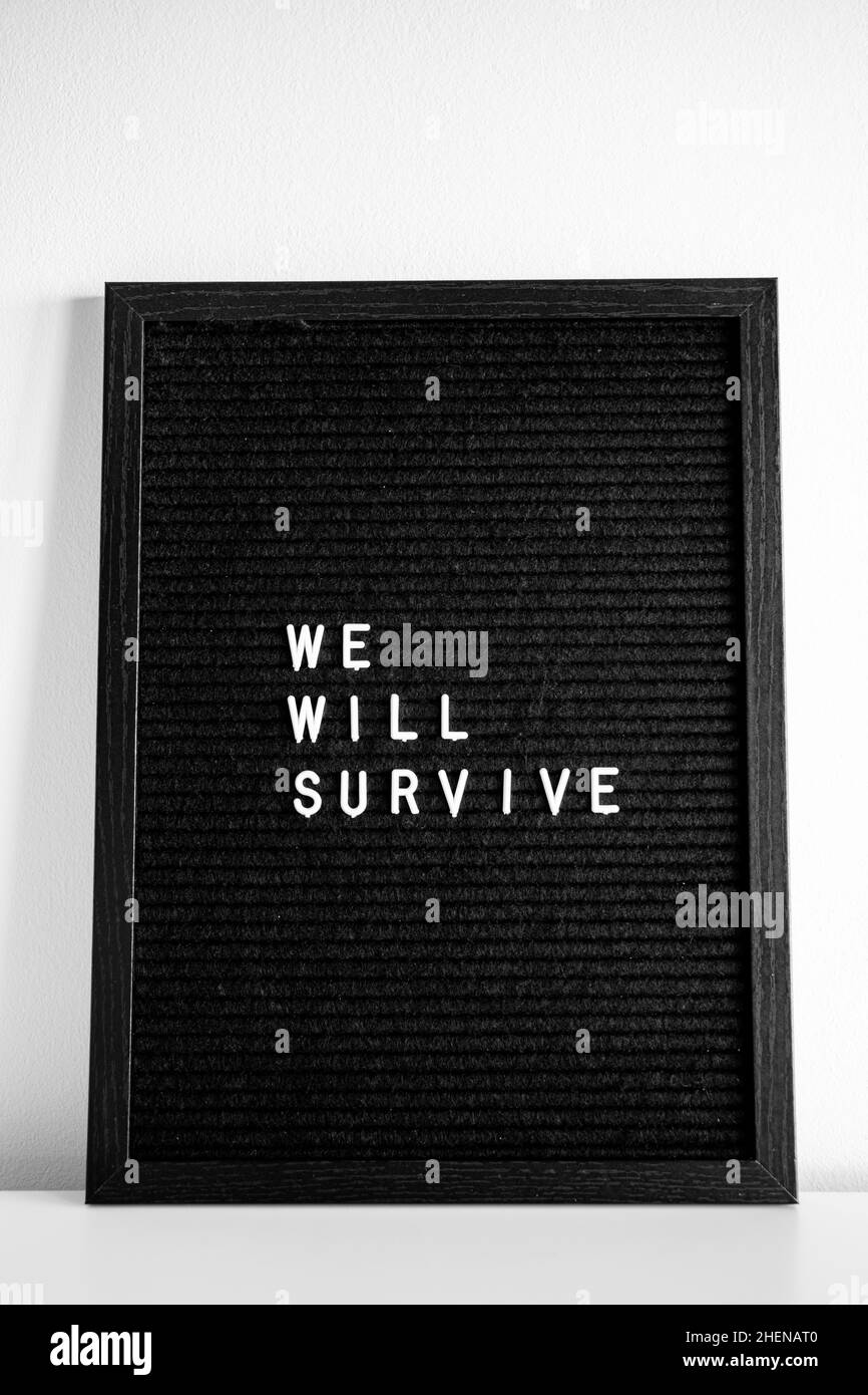 Corona virus inspirational encouragement we will survive quote black letter board white letters white background Stock Photo