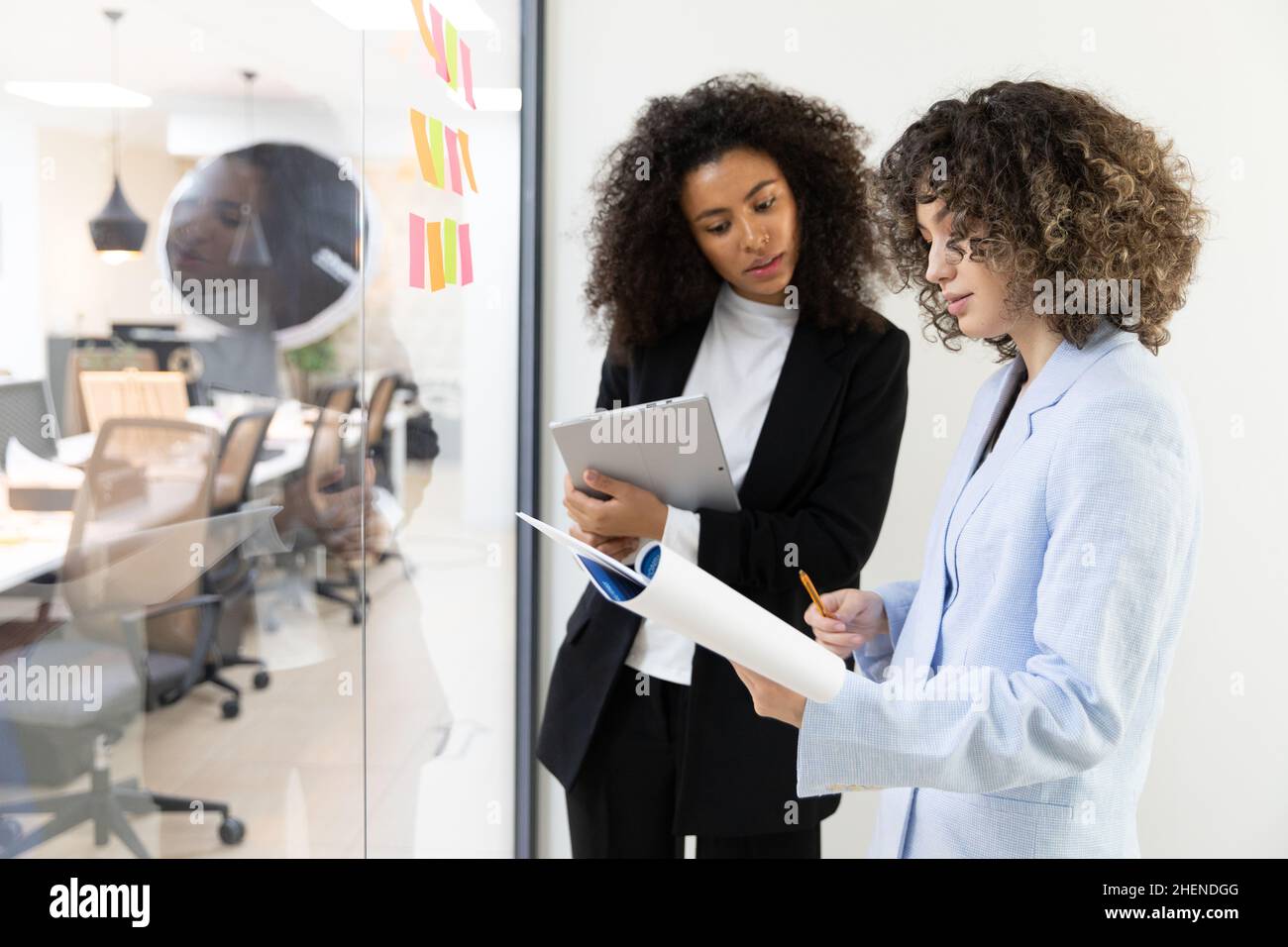 Multicultural coworkers using white board and doing brainstorming together. Co-working concept Stock Photo