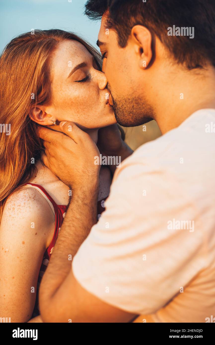 Close-up view of a couple kissing in a sunny field of wheat. eautiful summer landscape. Countryside landscape. Family weekend. Wheat field. Stock Photo