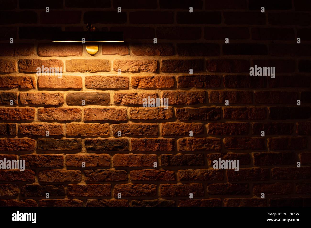 Brick wall illuminated by warm light from a lamp Stock Photo