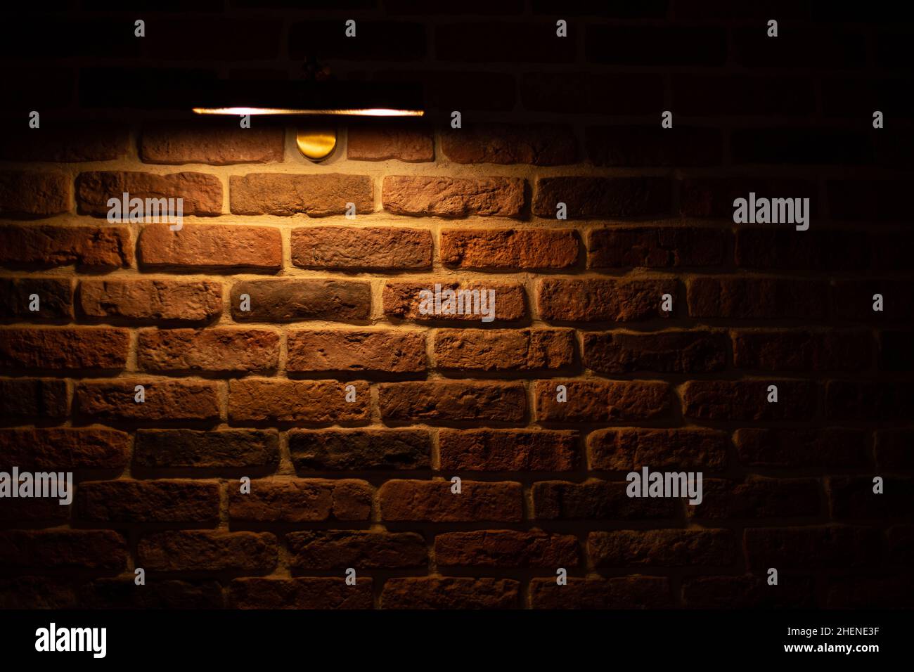 Brick wall illuminated by warm light from a lamp Stock Photo