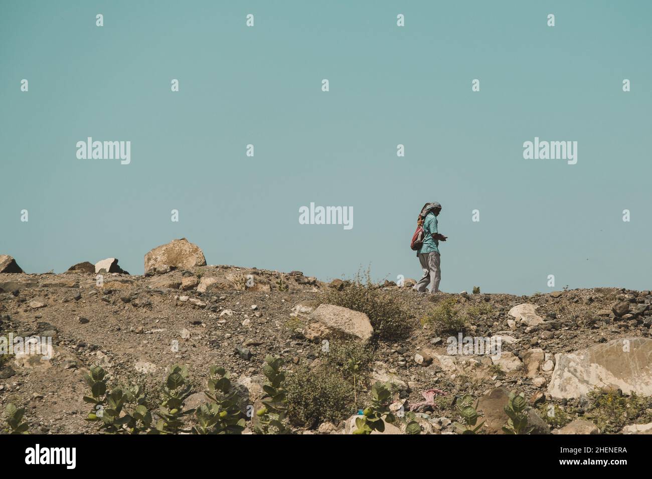 Djibouti, Djibouti - May 21, 2021: A Djiboutian alone man walking in the barren land. Editorial shot in Djibouti. Stock Photo