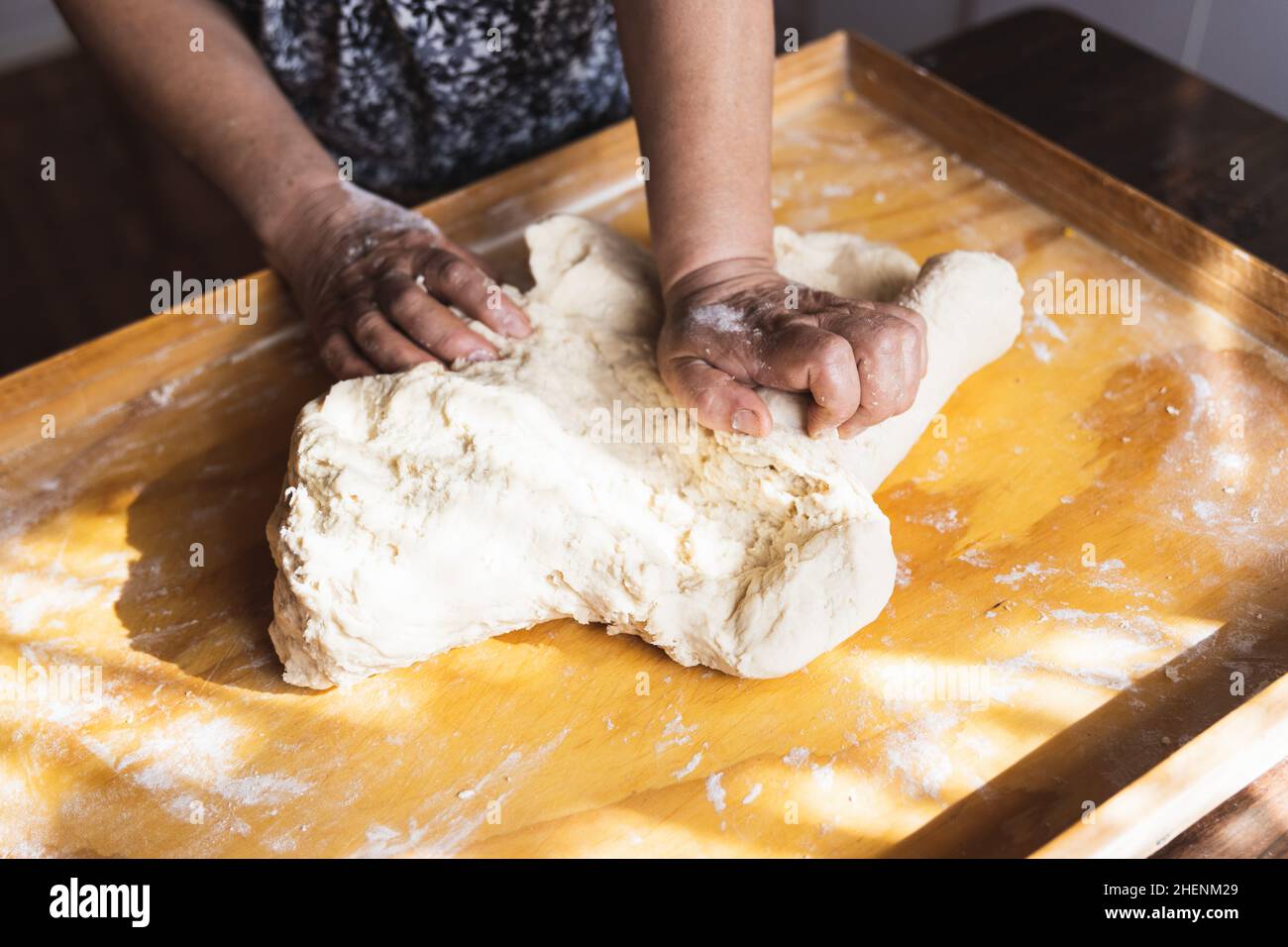 Old woman's hands kneading bread dough. Empanadas. Wooden table. Stock Photo
