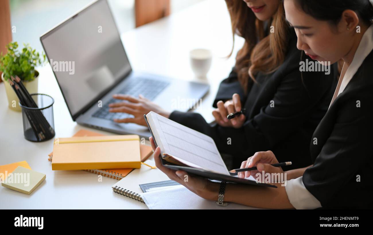 An Asian businesswomen discussing new ideas, brainstorming and taking a notes on notebook in the office. Stock Photo