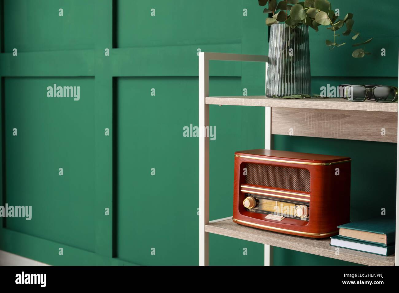 Bookcase with retro radio receiver near green wall Stock Photo Alamy