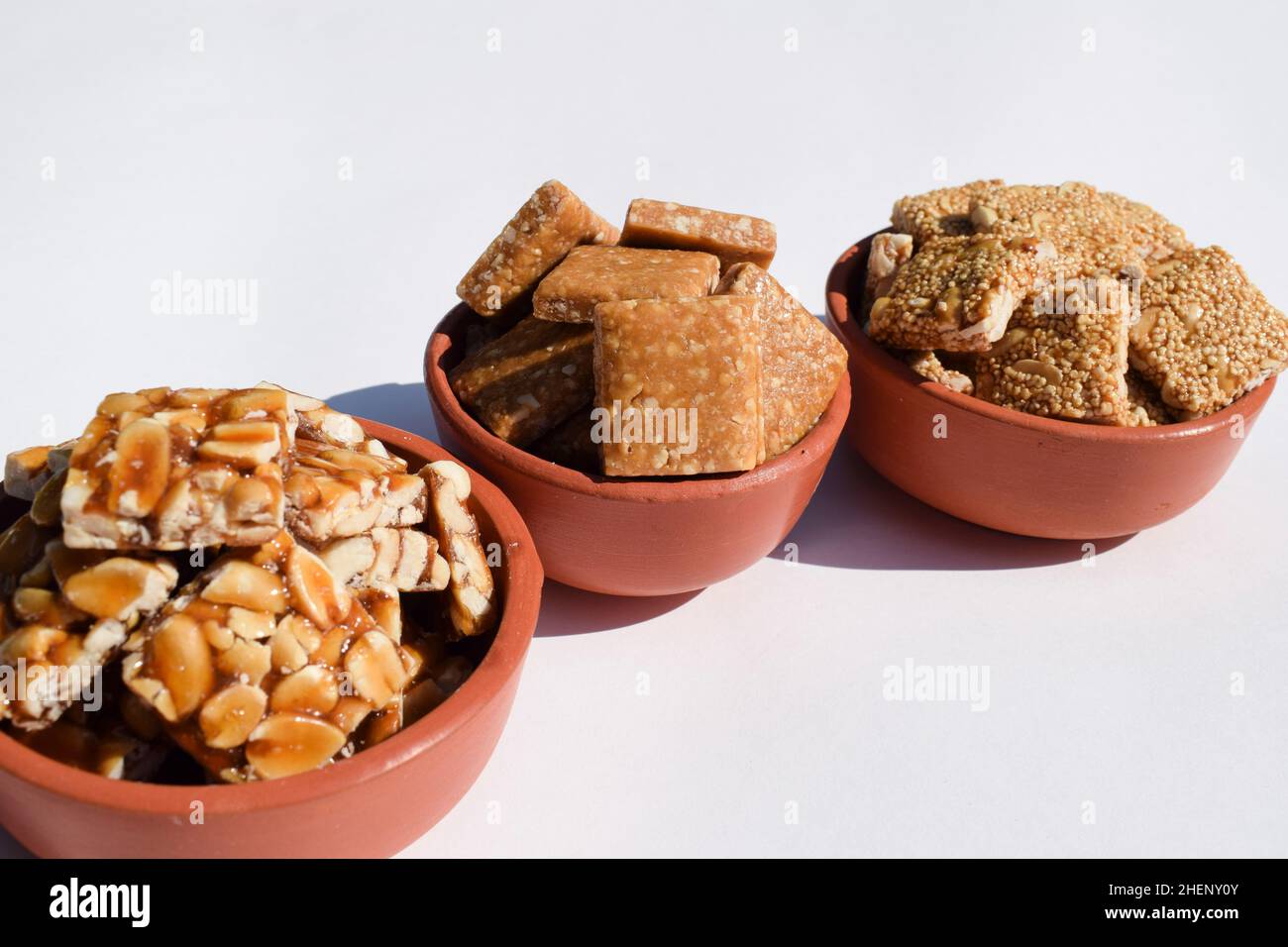 Peanut chikki, Crushed roaste peanut chiki, Rajgiri chikki or Amaranth brittle bars. Jaggery with peanut candy bars served in earthen bowls pot during Stock Photo