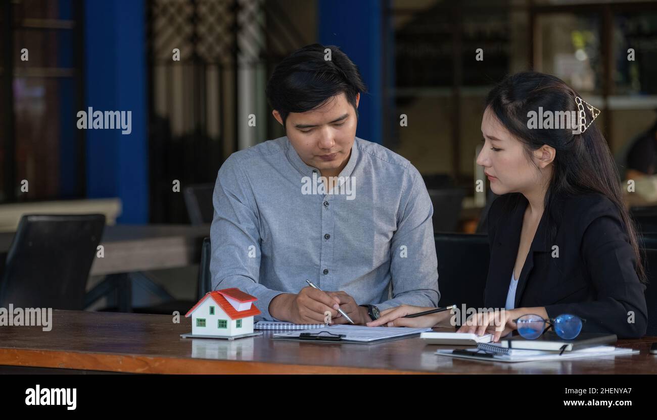 Real estate agent sales manager holding house model to customer after signing rental lease contract of sale purchase agreement, concerning mortgage Stock Photo