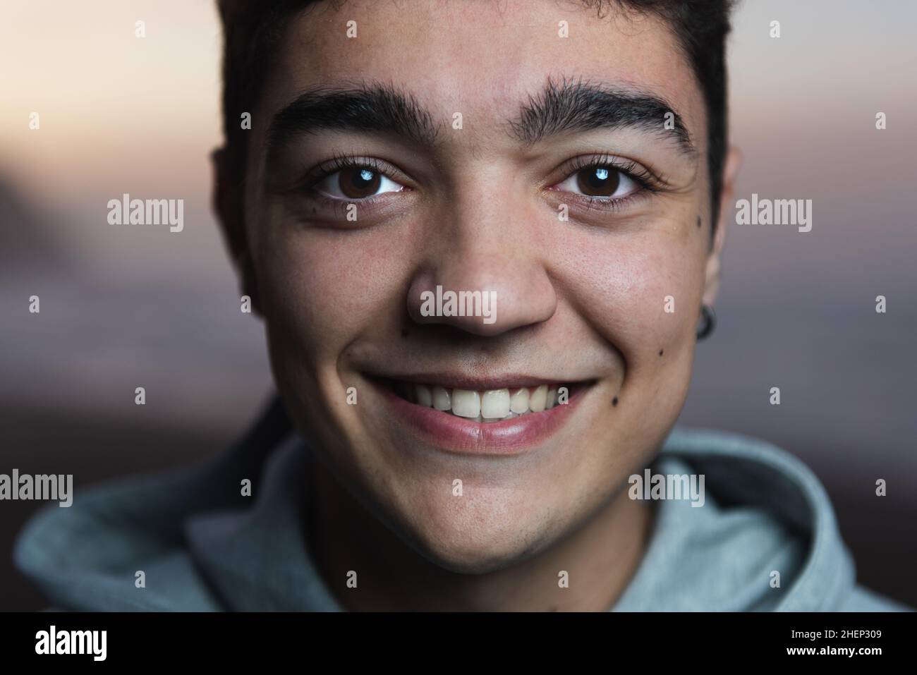Closeup portrait of hispanic teenager boy smiling and looking to the camera at sunset Stock Photo