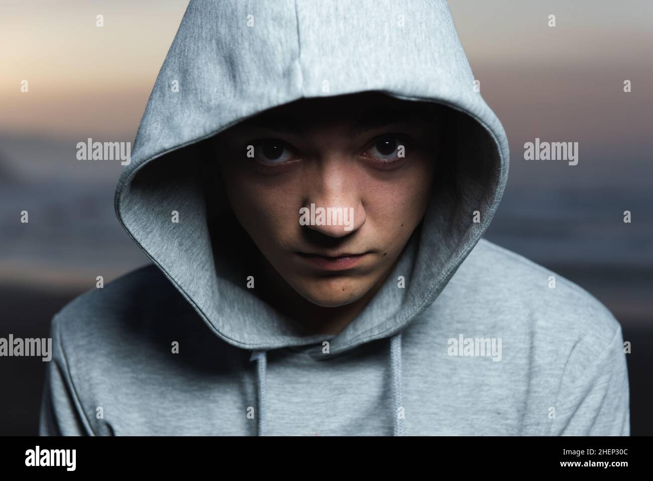Dramatic portrait of serious hispanic teenager looking to the camera and wearing a hoodie. Stock Photo