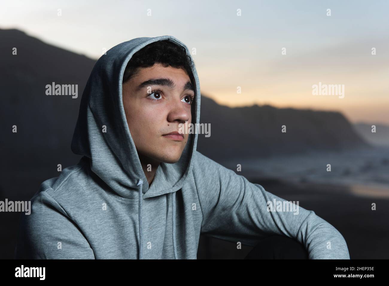Portrait of thoughtful adolescent wearing a sweater at sunset. Stock Photo