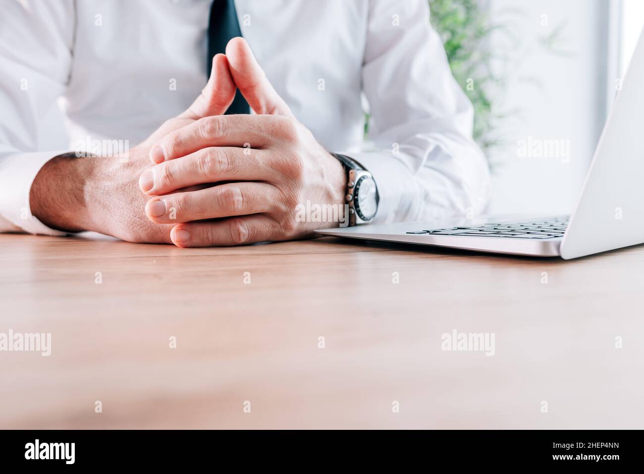 Uncomfortable businessman with hands clasped on office desk, business negotiation body language concept, copy space included and selective focus Stock Photo