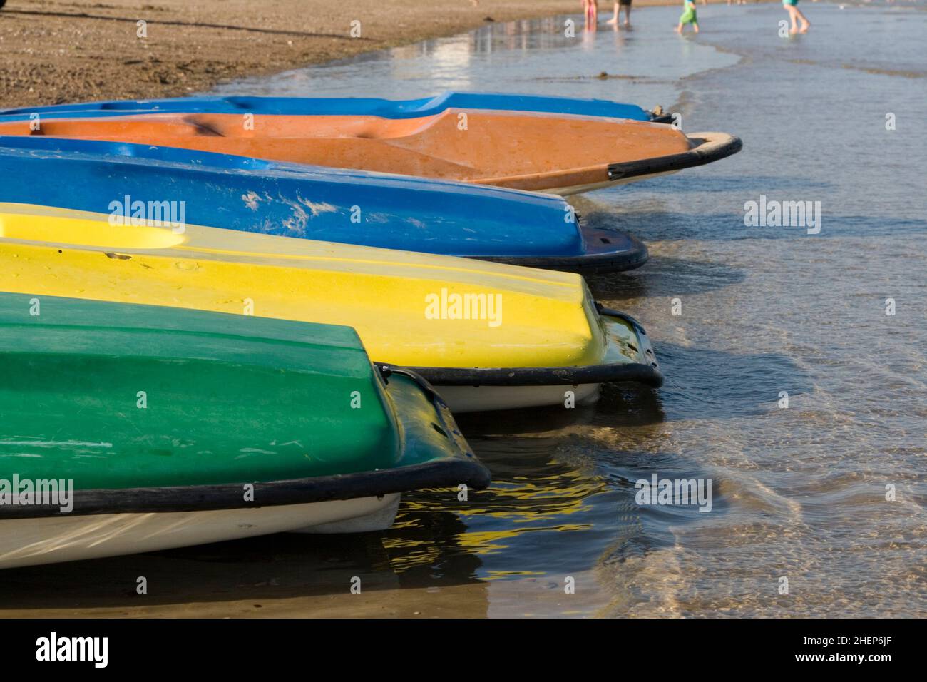 Multi colour canoes for hire at the waters edge on the beach at Weymouth, Dorset on the South coast of England Stock Photo