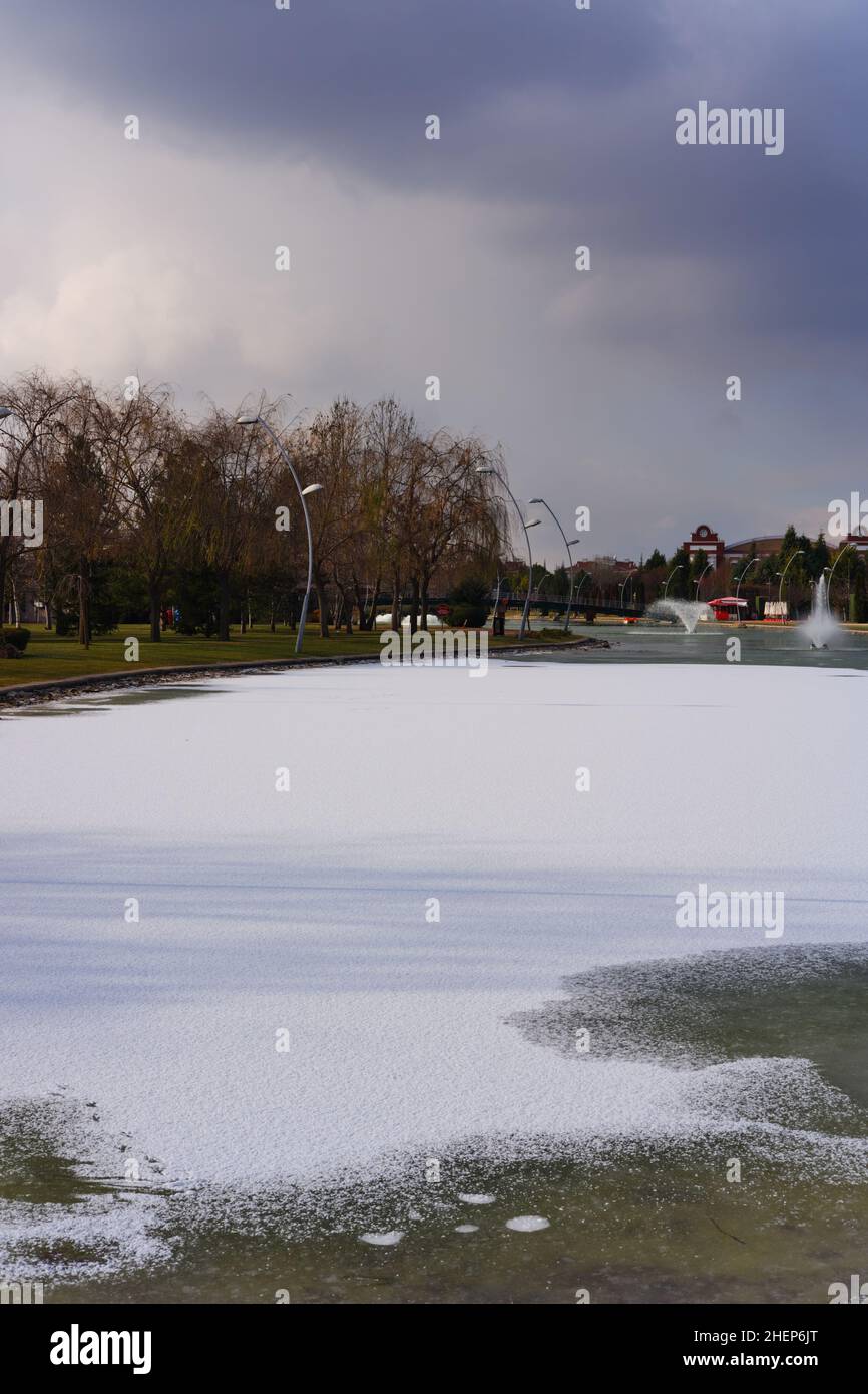 Partly frozen artificial lake and fountain at a city park Stock Photo