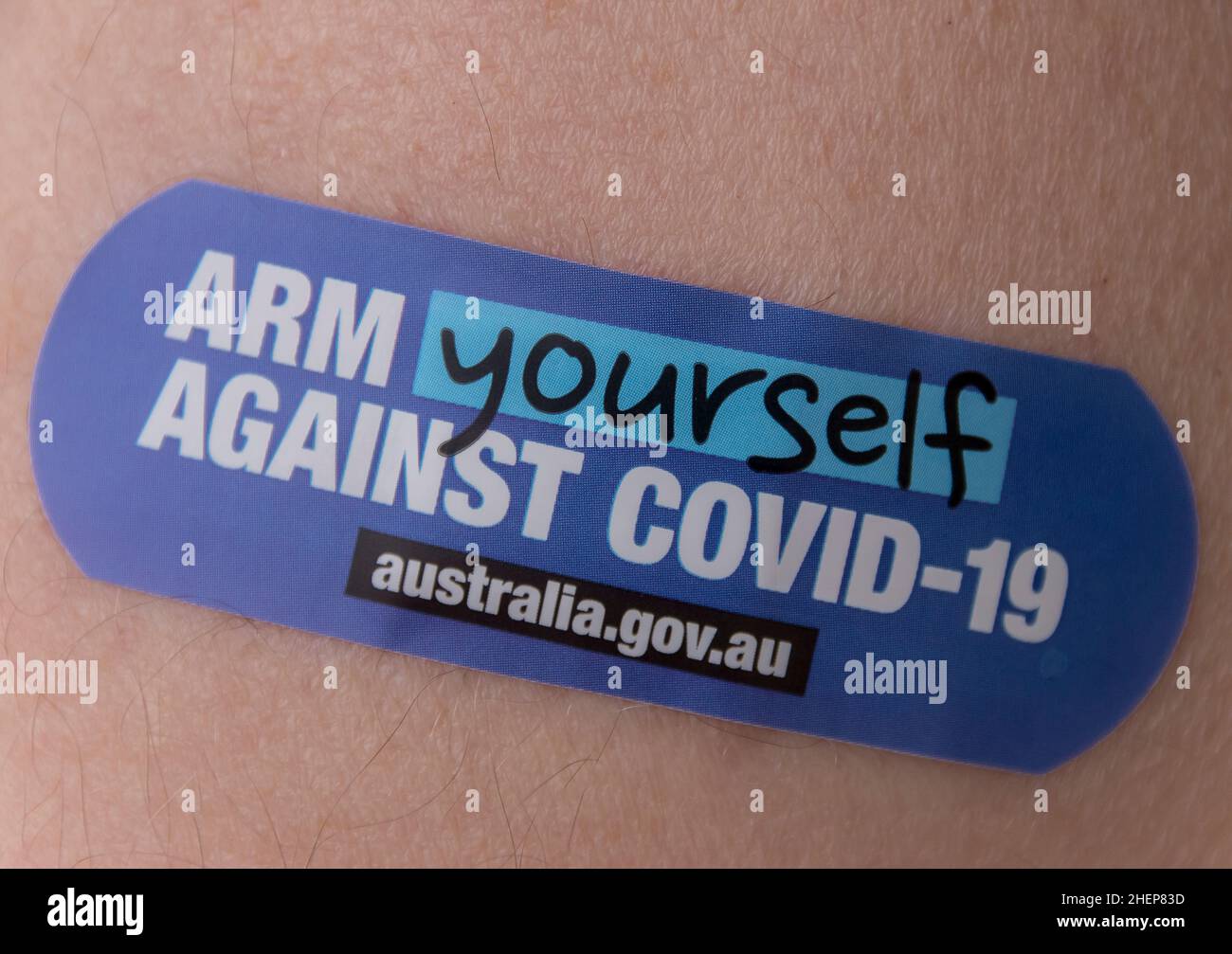 Australian government slogan on plaster (band-aid) stuck on arm after vaccination. Dressing on arm after jab. Public health message. Stock Photo