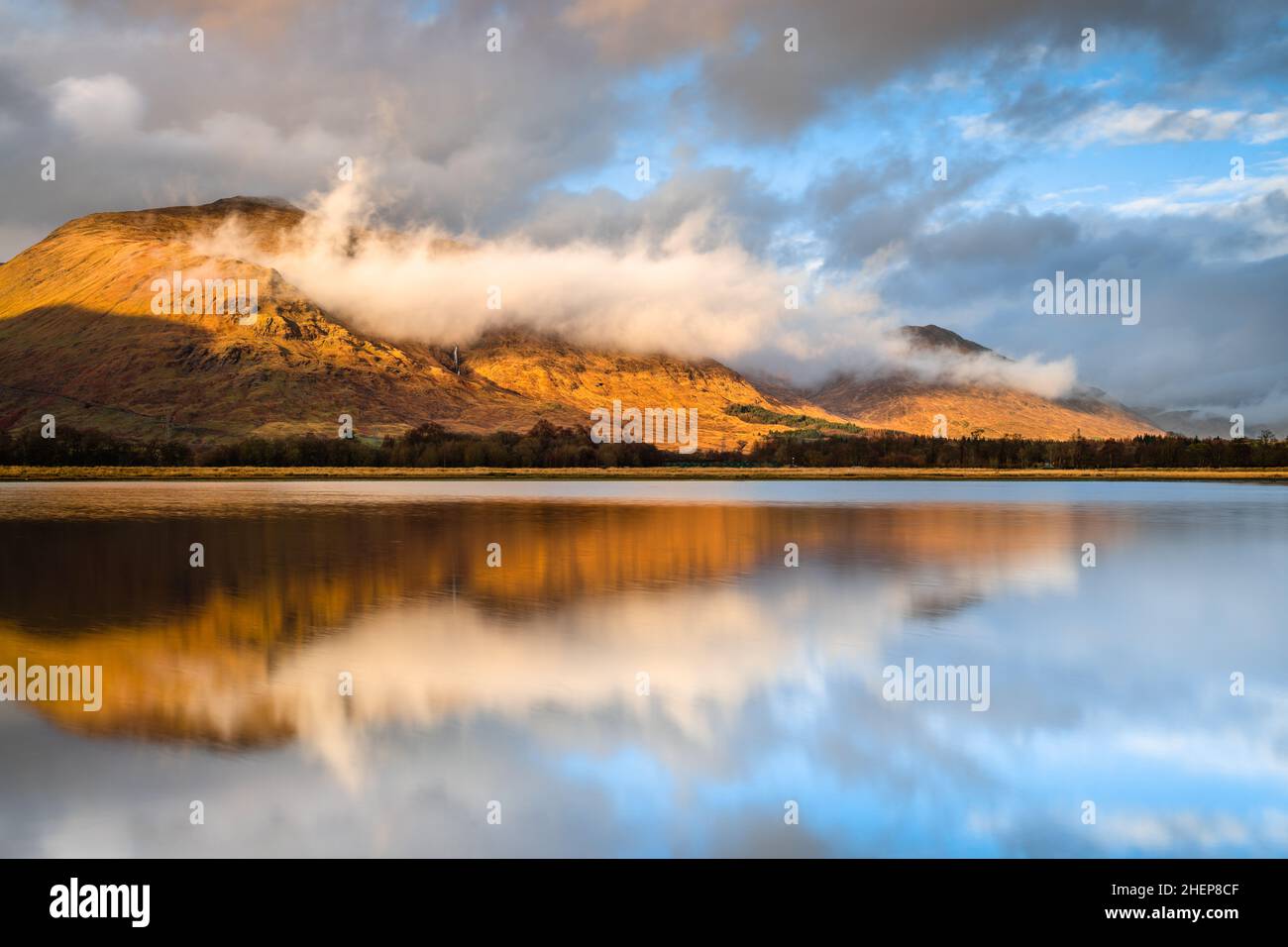 Kilchurn Castle, Loch Awe, Argyll & Bute, Scotland. Warm sunset colours striking the mountains & lighting up castle, with dramatic storm clouds in sky. Stock Photo