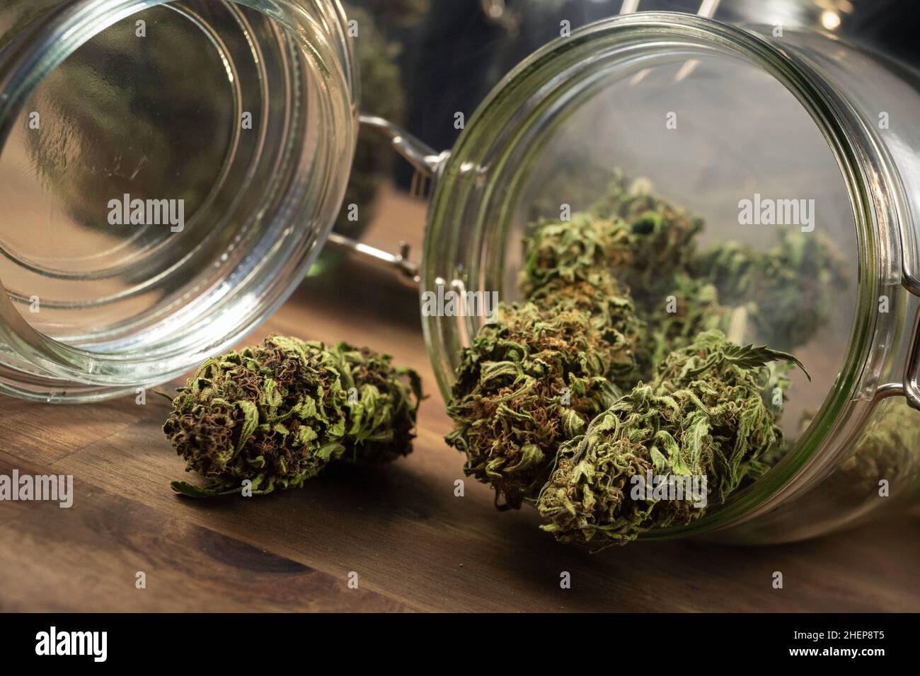 Dry CBD hemp buds, cannabis potheads spilled from a glass jar on the table. Stock Photo
