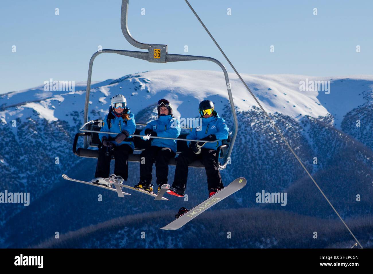 Ski and snowboard instructors riding the chairlift on a bluebird day at Falls Creek Ski Resort, Victoria, Australia. Stock Photo