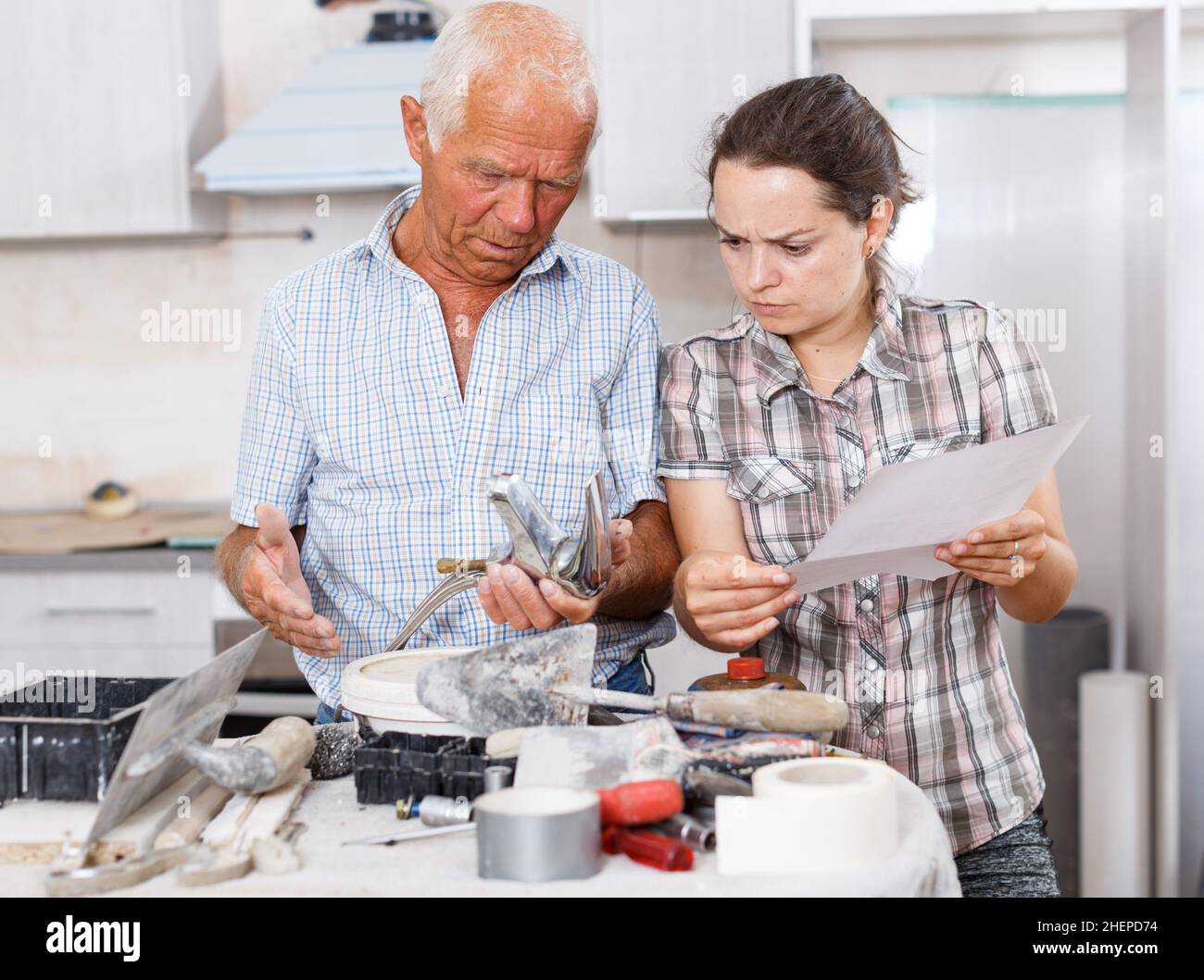 Woman and father discussing instructions for mixer tap Stock Photo