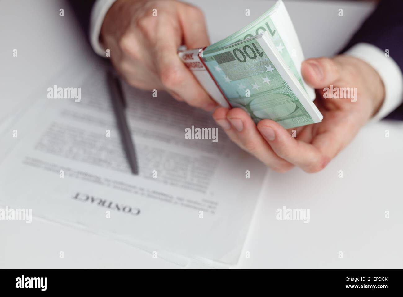 Man in suit counts wad of money before signing contract. Close up of hands with money euro Stock Photo