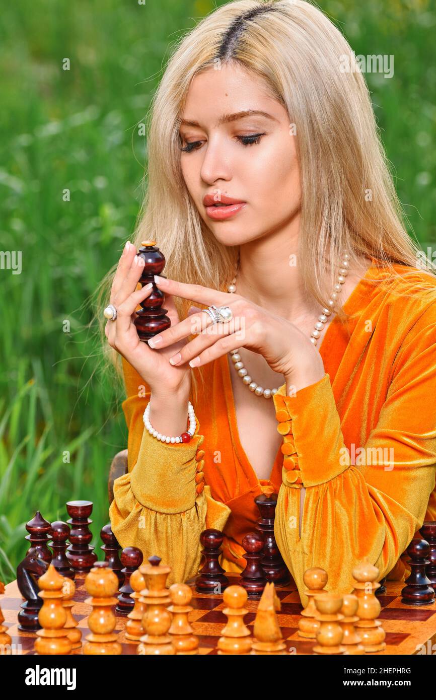 Woman plays chess in nature in the field Stock Photo