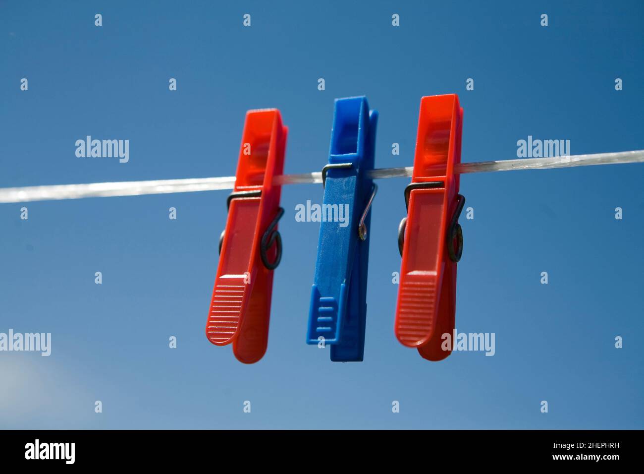 three blue and red clothespins at a clothesline , Austria Stock Photo