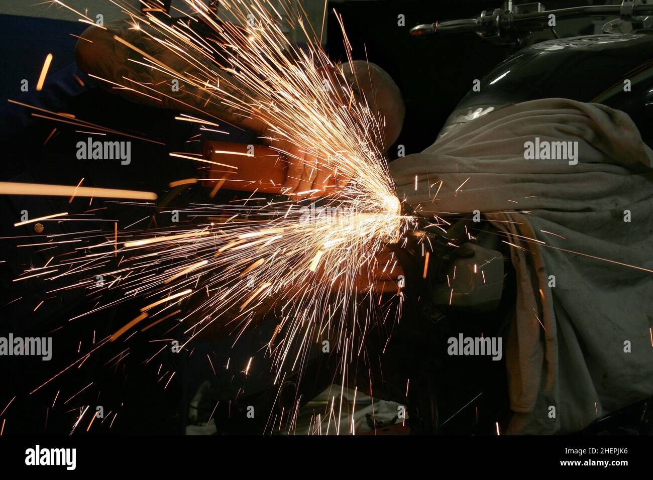 working with an angle grinder at a motorcycle, spraying sparks Stock Photo