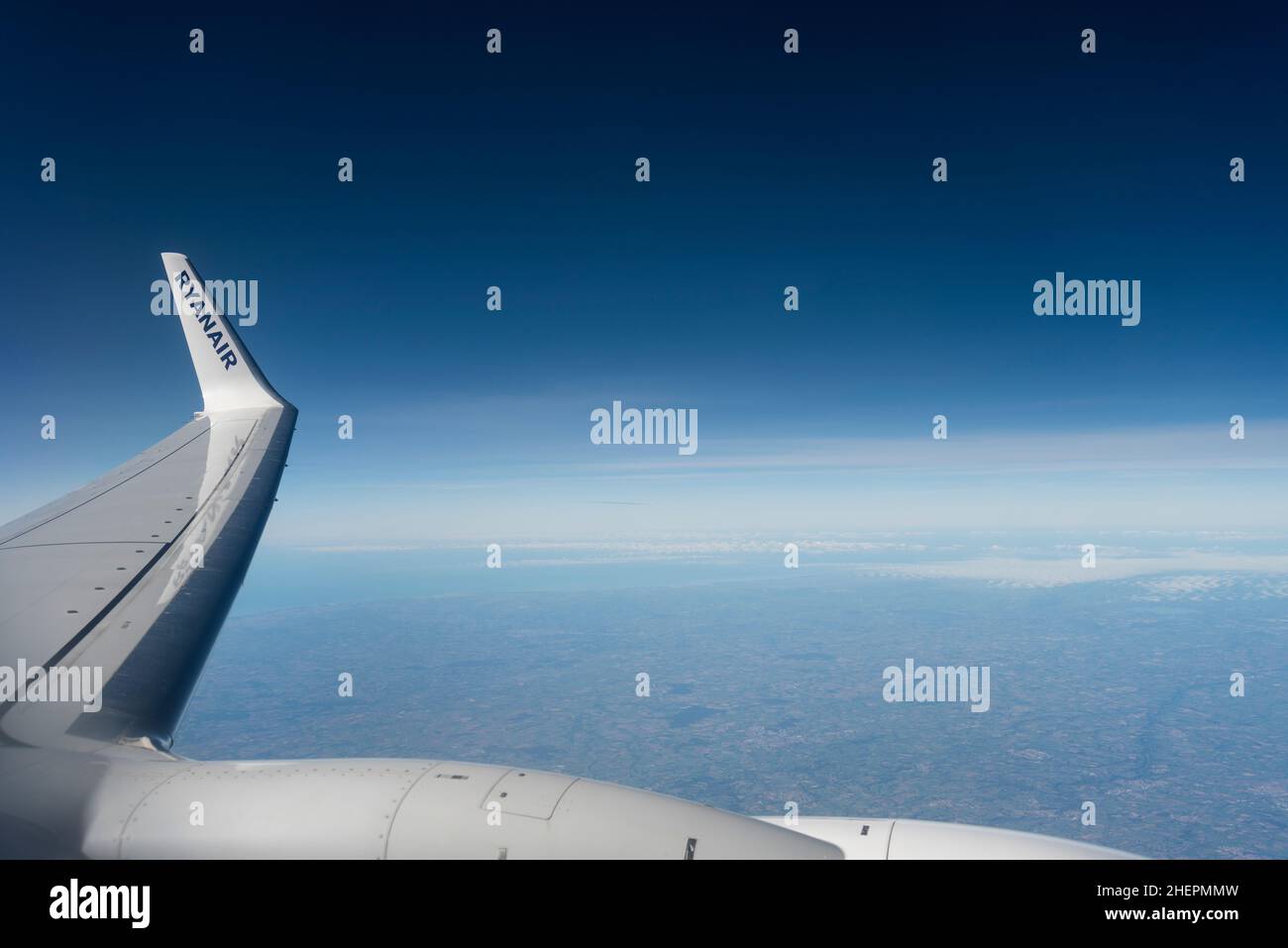 Wingtip of a Ryanair Boeing 737 flying at high cruise altitude over France, with deep blue sky. Ryanair titles on wing tip winglet, over light cloud Stock Photo