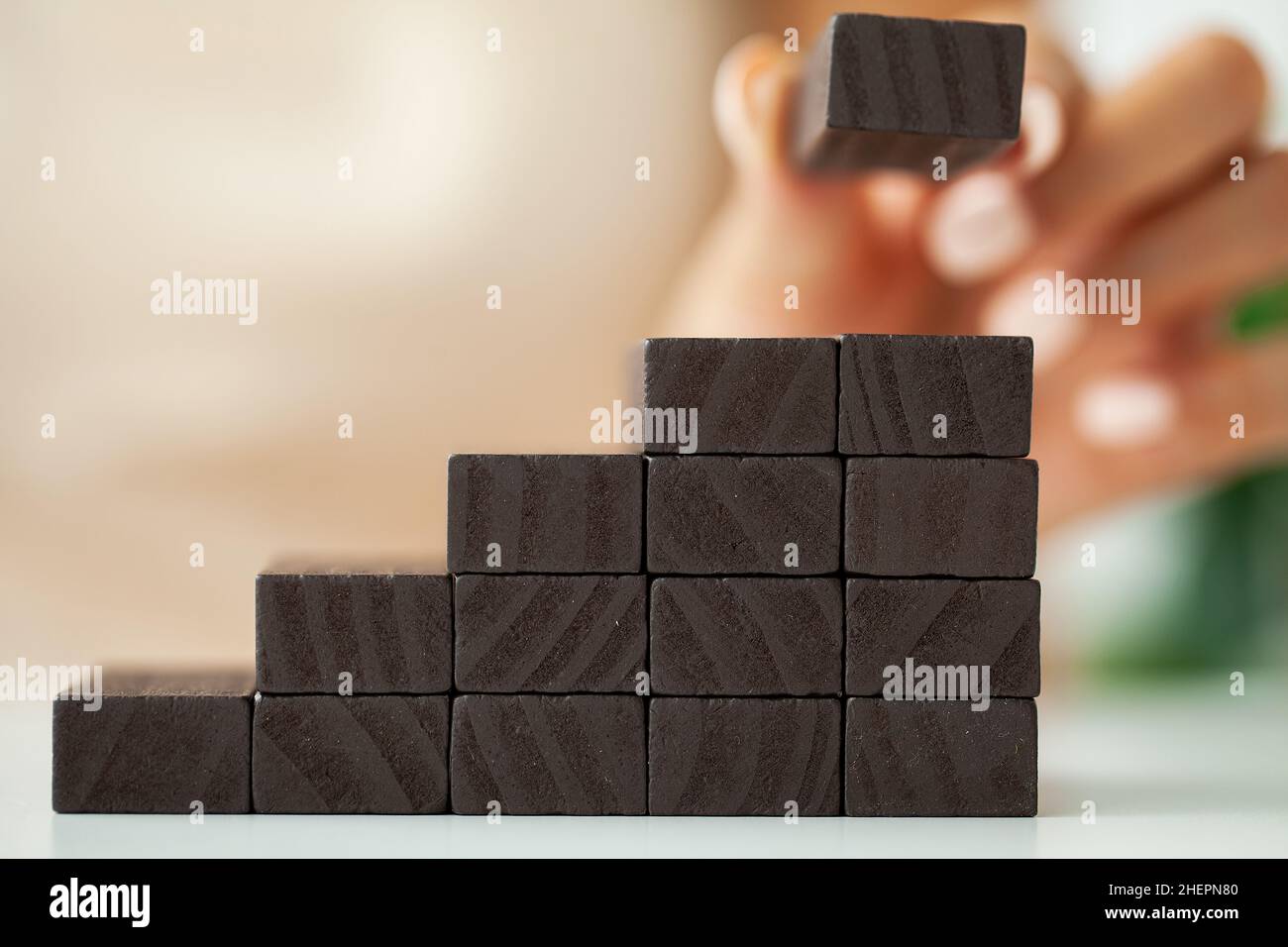 Hand putting wood cube on top of wood block stacking as step stair ...