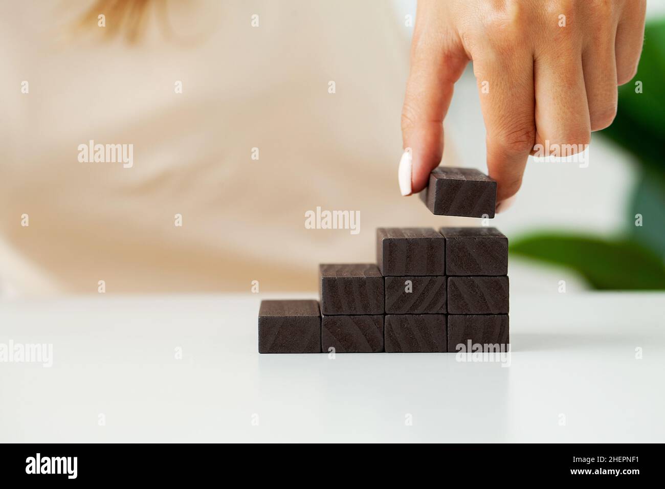 Hand putting wood cube on top of wood block stacking as step stair ...