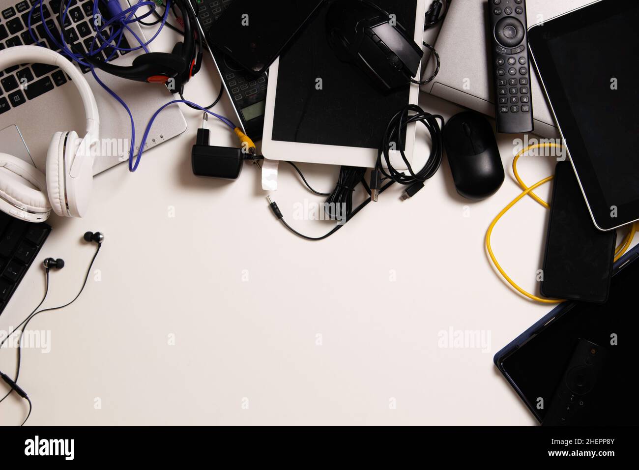 Top view to old laptop computers, digital tablets, mobile phones, many used electronic gadgets devices on white table. Planned obsolescence Stock Photo