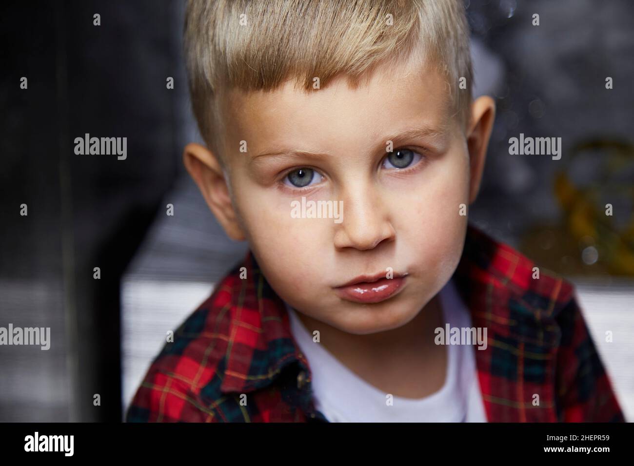 Portrait of handsome serious adorable kid close up. Atmospheric, aesthetic home for New Year's Eve. Silver cozy home, good mood. Stock Photo