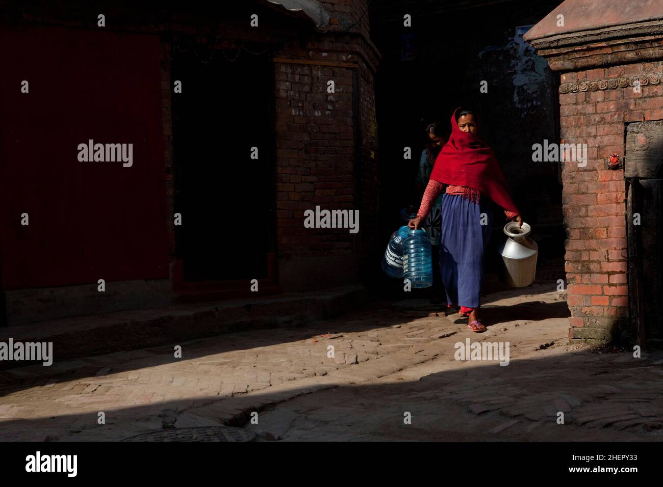 Local Newari woman collecting water in the UNESCO World Heritage city of Bhaktapur, Nepal. Stock Photo