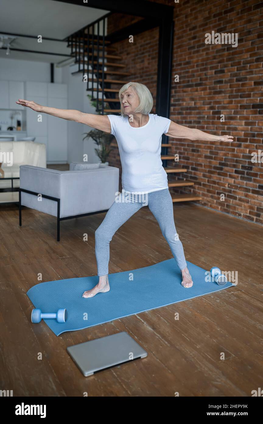 A senior woman standing in a warrior pose Stock Photo