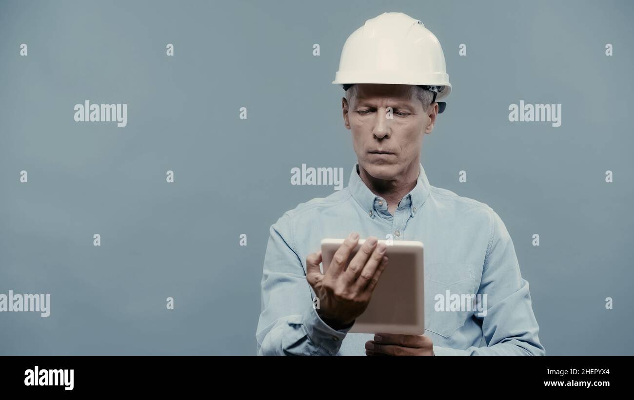 Engineer in hardhat using digital tablet isolated on grey Stock Photo