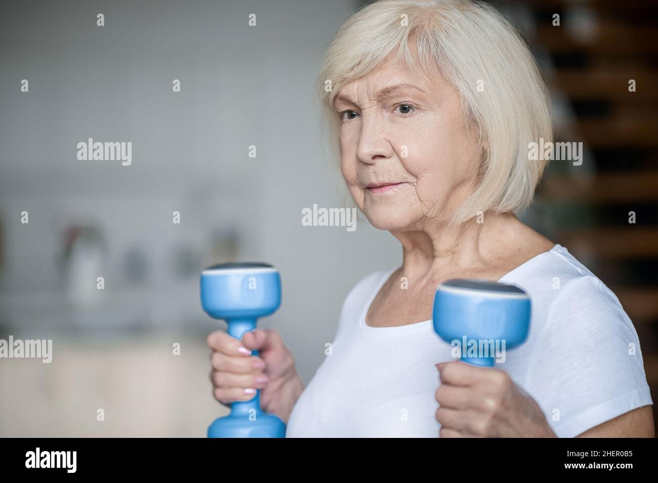 Active senior woman with dumbbells in hands doing her workout Stock Photo
