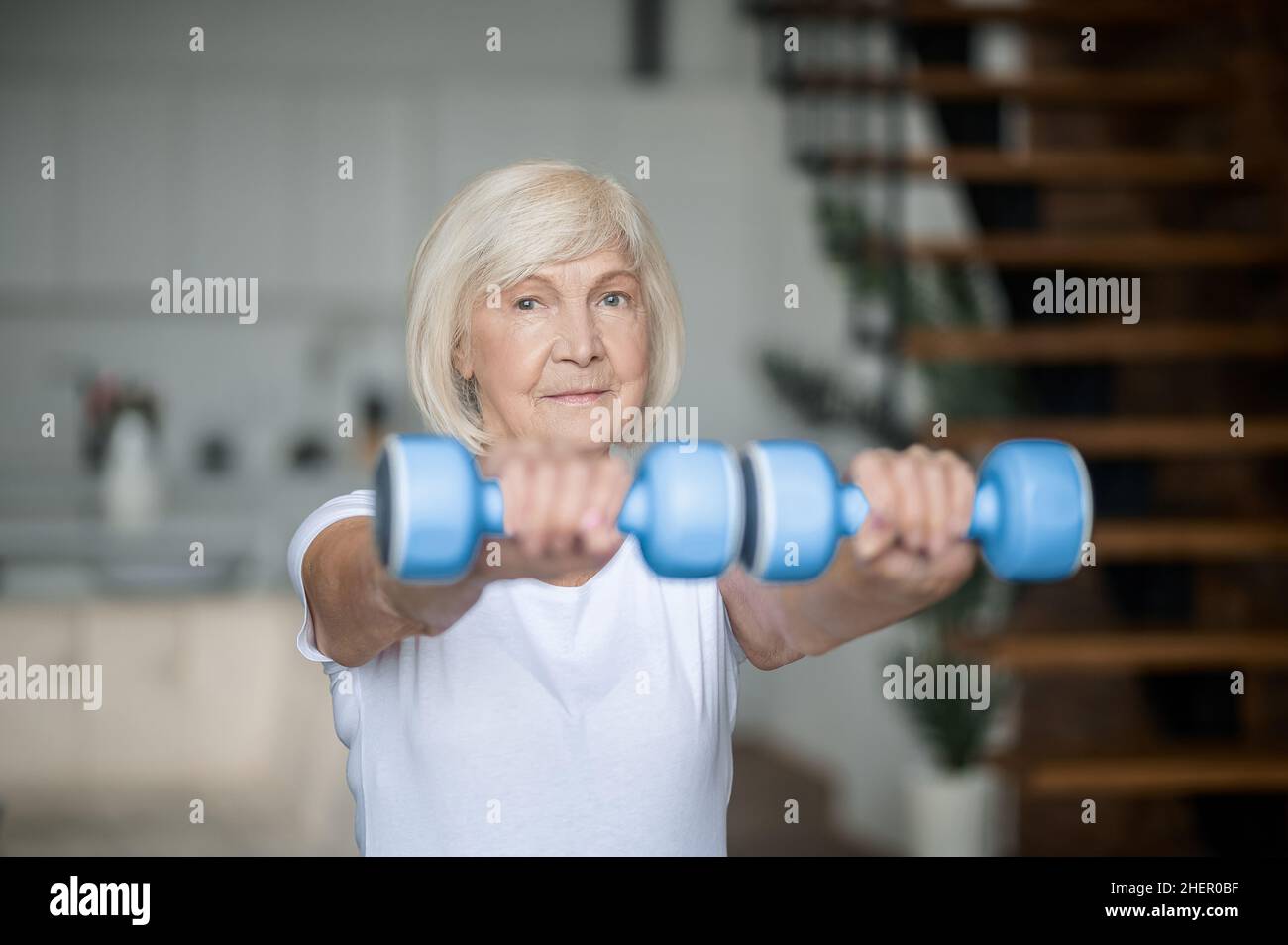 Active senior woman with dumbbells in hands doing her workout Stock Photo