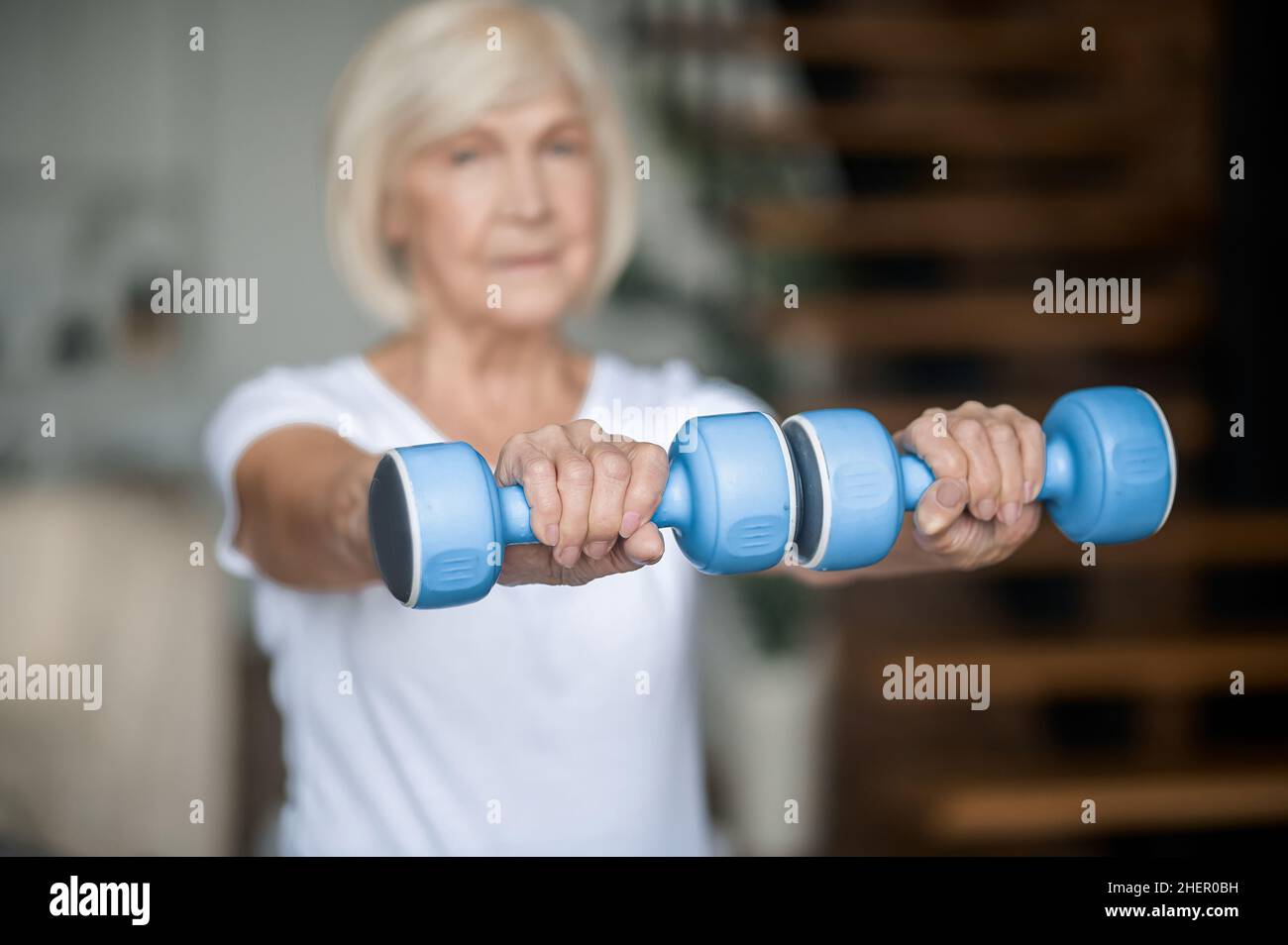 Active senior woman with dumbbells in hands doing her workout Stock Photo
