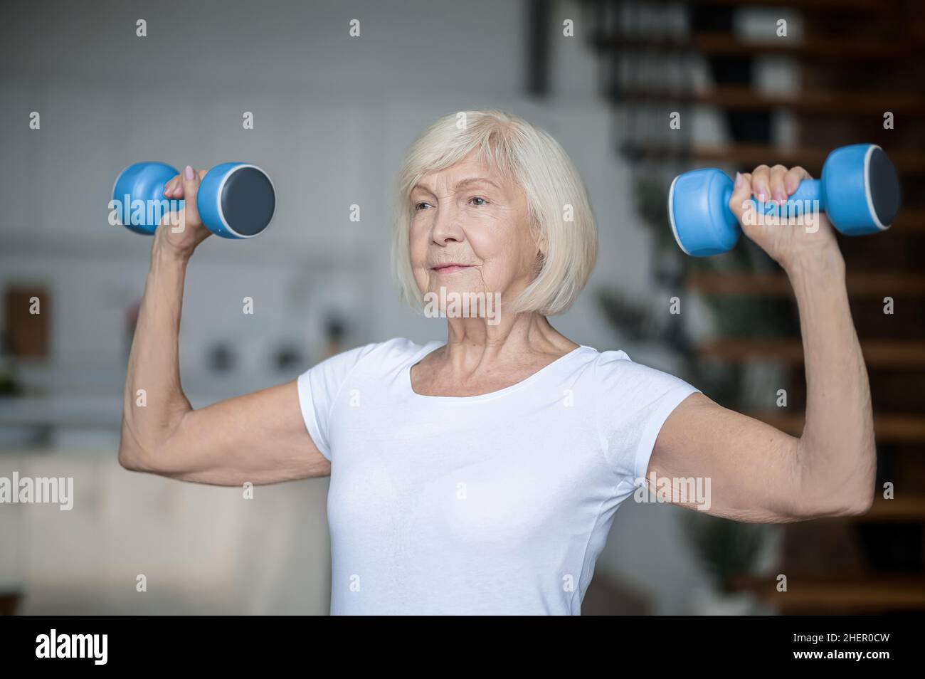 Active senior woman with dumbbells in hands doing her workout Stock Photo