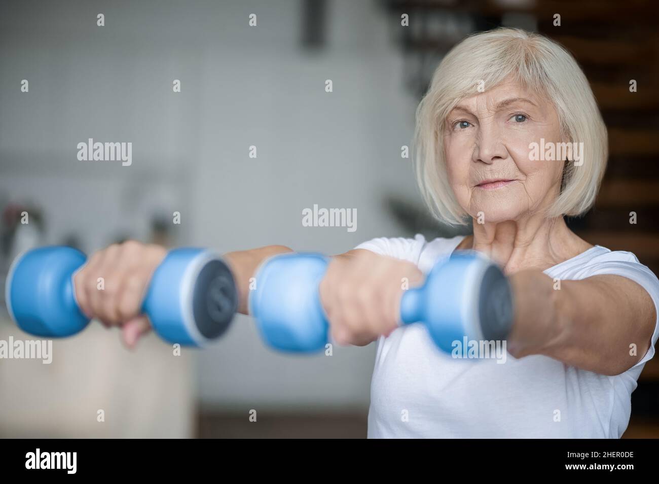 Active senior woman with dumbbells in hands doing her workout Stock Photo